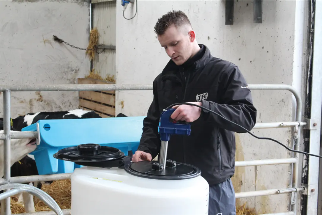 Electric Milk Warmer E3000 on a white milk cart; blue handheld unit; worker wearing JFC Agri jacket.