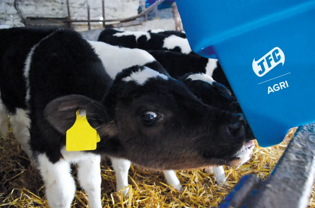 6-teat compartment calf feeder in blue with JFC Agri logo; calf feeding beside straw.