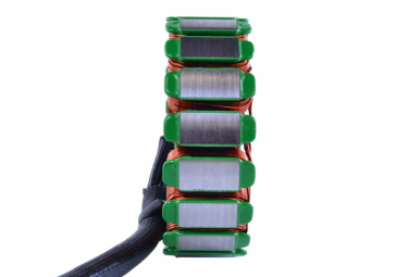 Generator stator with copper windings and green end caps, stacked laminated cores.