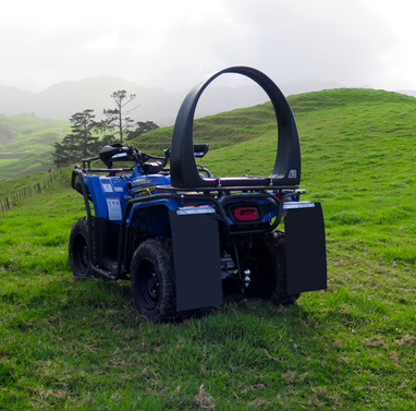 QuadGuard CPD and Mounting Trax, black, mounted on a blue ATV in a grassy hillside field
