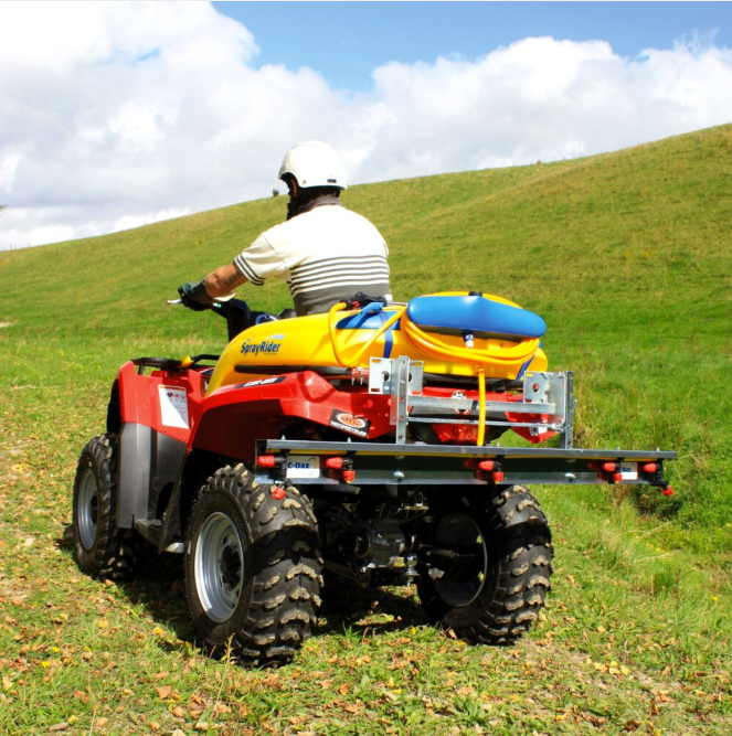 C-Dax MultiBoom ATV spray boom mounted on a red quad with a yellow spray tank in a grassy field.