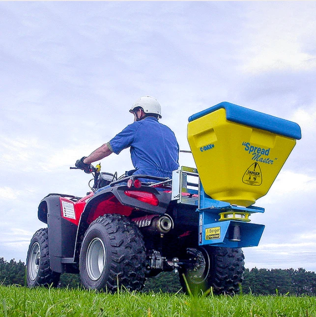Spreader C-Dax SpreadMaster SM70 FD mounted on an ATV with a yellow hopper and blue frame