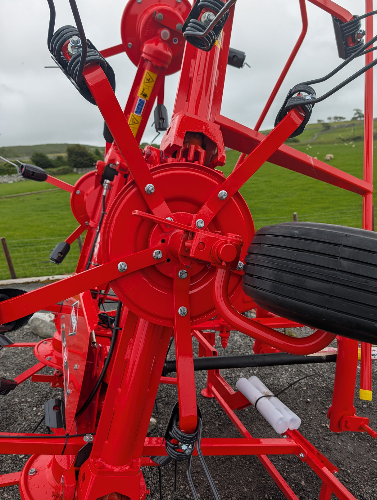 Kuhn GF582 six-rotor tedder with red frame, black hydraulic hoses and large tires.