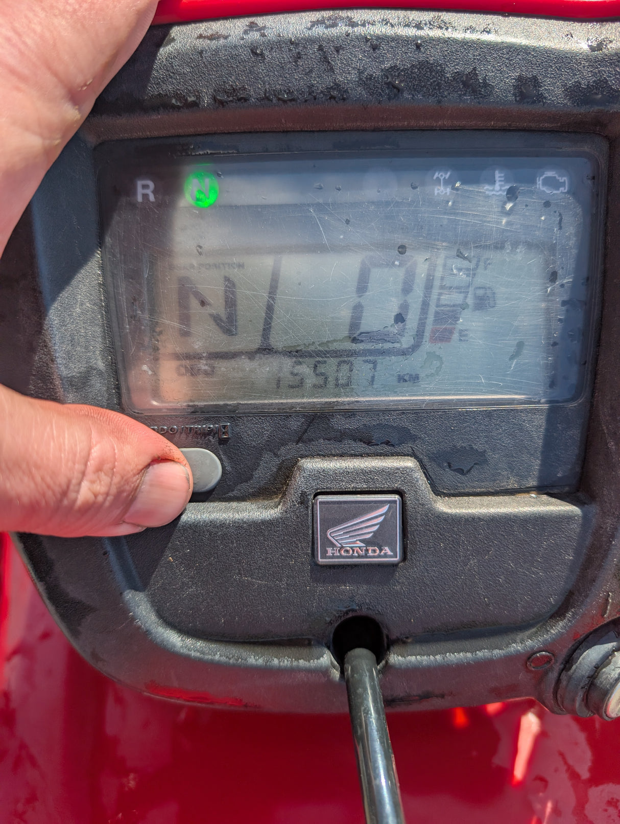 Honda TRX 500 ATV dashboard in red with a green neutral indicator and Honda emblem