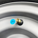 ATV wheel with a silver rim, brass valve stem, and blue OP03 tag visible.