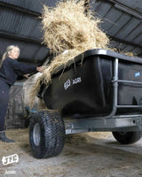 JFC Agri ATV tip trailer, black, loaded with hay inside a barn