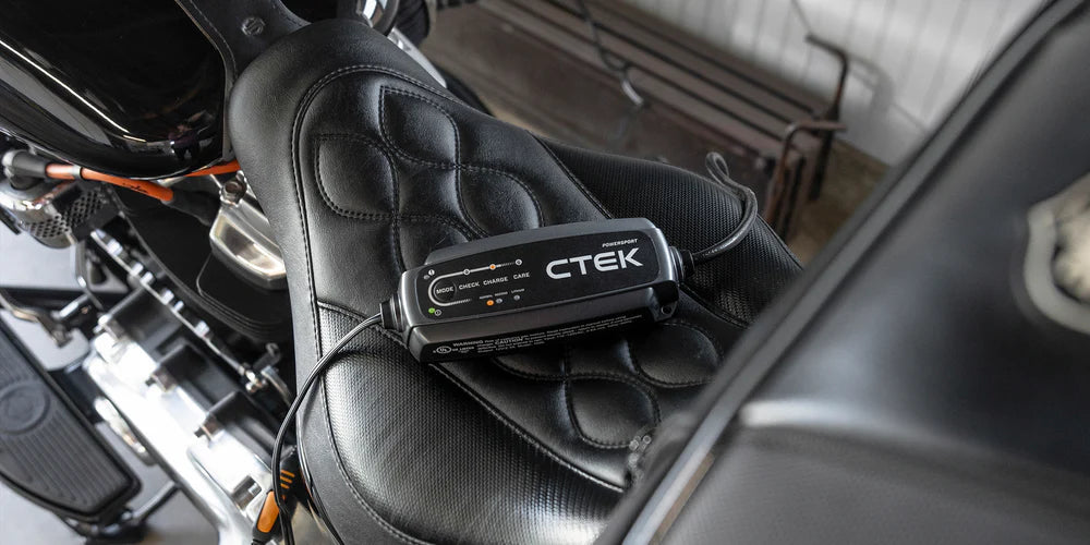 CTEK CT5 Powersport 12V battery charger on a black motorcycle seat.