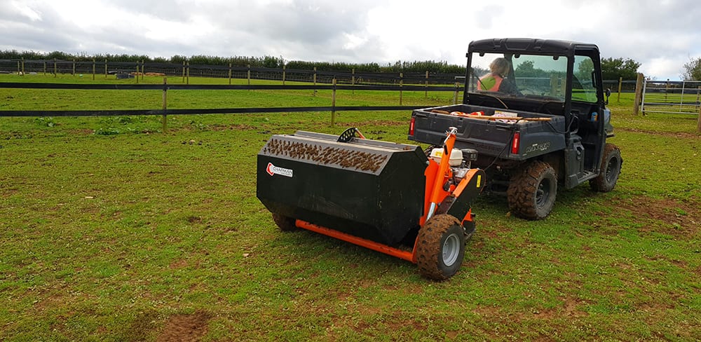 Chapman PC120 paddock cleaner with orange frame and black hopper attached to a utility vehicle in a paddock