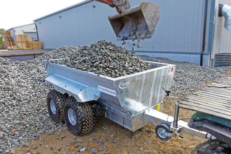 Chapman DT100 hydraulic dump trailer unloading gravel; silver metal ATV/UTV trailer.