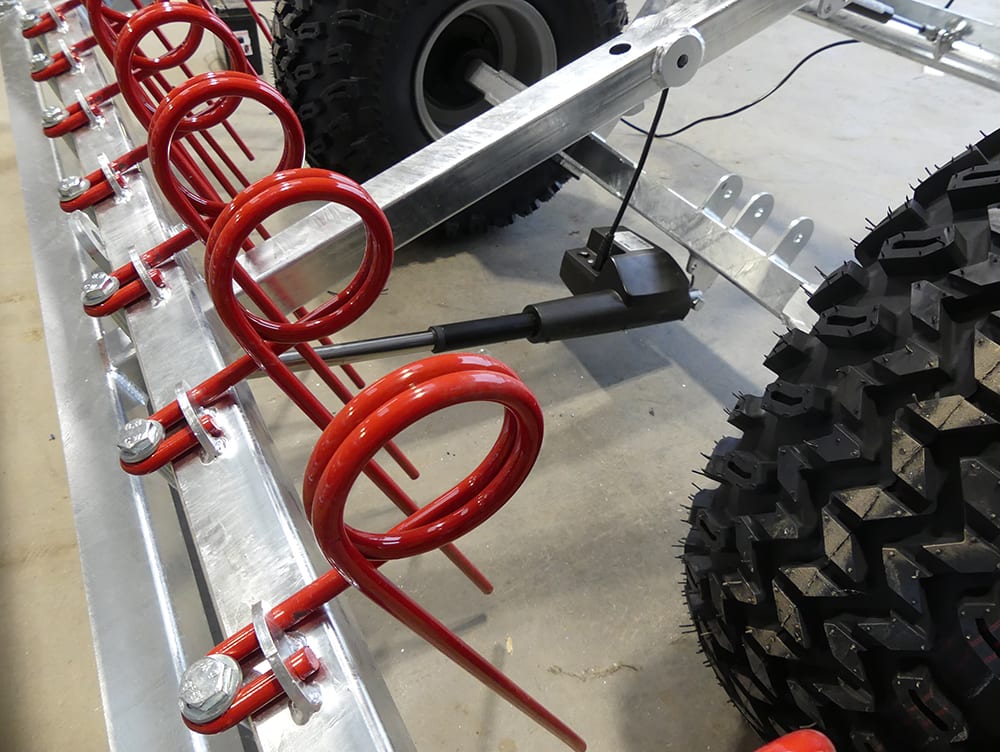Chapman MG250 Arena Leveller, galvanised frame with red coil spring assemblies and large off-road tires.