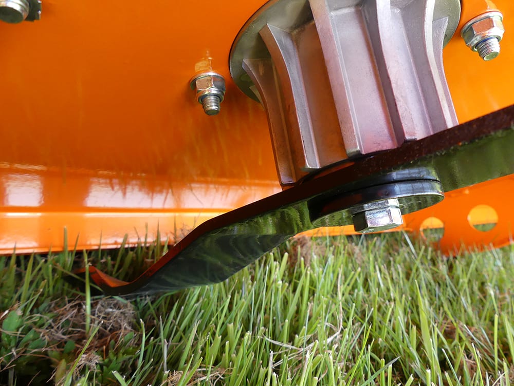 Chapman RM Series ATV Rotary Paddock Topper on orange frame; visible mounting hub bolt and curved black guard near grass.