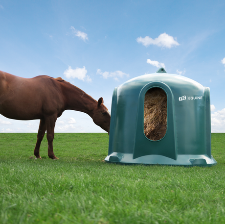 JFC Haybell Round Bale Cover Feeder, green plastic unit with JFC Equine branding on grass.