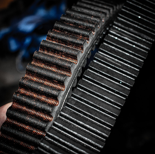 Gates G-Force Redline CVT drive belt close-up, black cogged belt with orange reinforcement cords