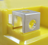 MBTX24U Motobatt battery terminal clamp on a yellow battery housing; silver metal block with a circular hole.