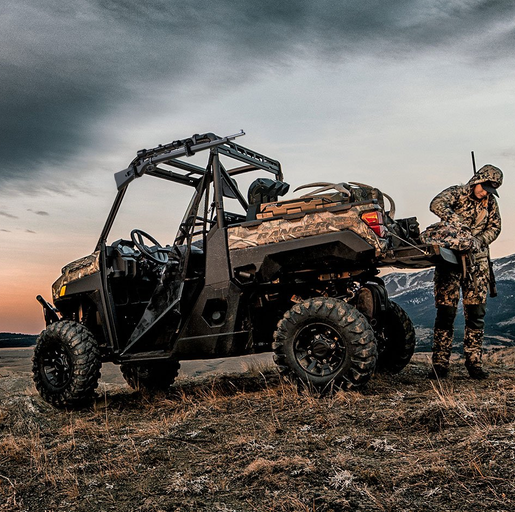 Gun rack - Universal UTV (Aluminium) mounted on black off-road UTV; hunter in camo nearby.
