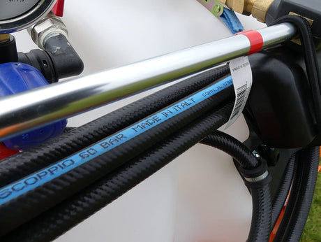 Chapman weed wiper tractor-mounted with black braided hoses and a silver metal bar
