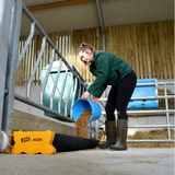 JFC Agri Corri Feed Trough 2000mm x 300mm (70L) in a barn; worker pours grain from a blue bucket.