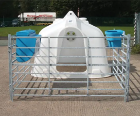 JFC Agri white compact calf hutch with metal pen and two blue feed troughs.