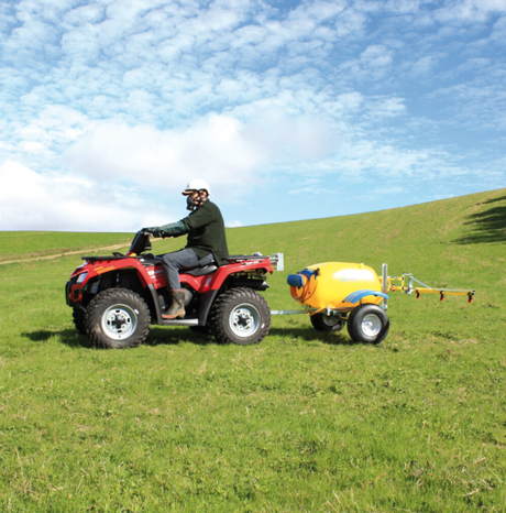 C-Dax ATV sprayer Gen 2 with yellow spray tank hitched to a red ATV in a grassy field