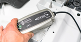 CTEK MXS 3.8 12V battery charger and maintainer; silver/black unit connected to a car battery with a green MODE button