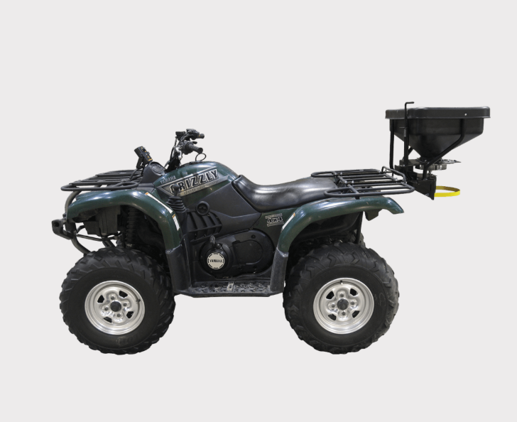 Fimco ATV Dry Material Spreader 12V DMS mounted on a green ATV with rear hopper and rain cover