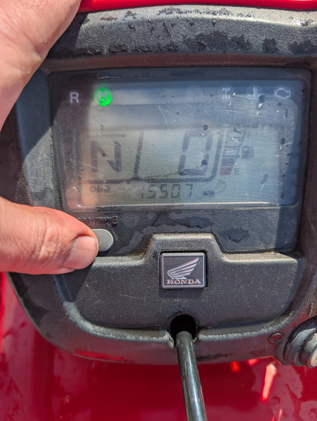 Honda TRX 500 ATV dashboard in red with a green neutral indicator and Honda emblem