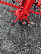 Kuhn GF582 6-rotor tedder for straw hay and silage, red frame with black tines and wheel on gravel.