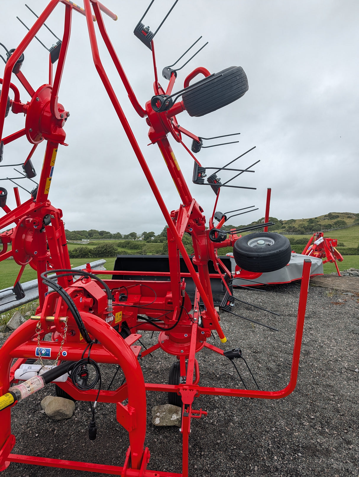 Kuhn GF582 6-rotor tedder in red, with black tine arms; agriculture machinery for straw hay and silage