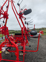 Kuhn GF582 6-rotor tedder in red, with black tine arms; agriculture machinery for straw hay and silage